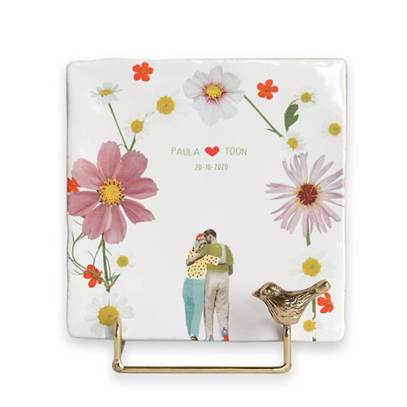 Gouden tegelhouder met bloemen en omarmend koppel op tegel