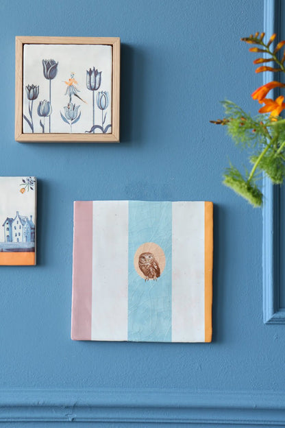 Geslaagd cadeau tegeltje uil centraal op blauw-witte achtergrond muur