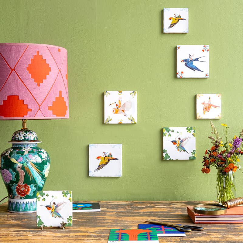Tegeltje vogels kleurrijk op groene muur, naast bloemen en lamp