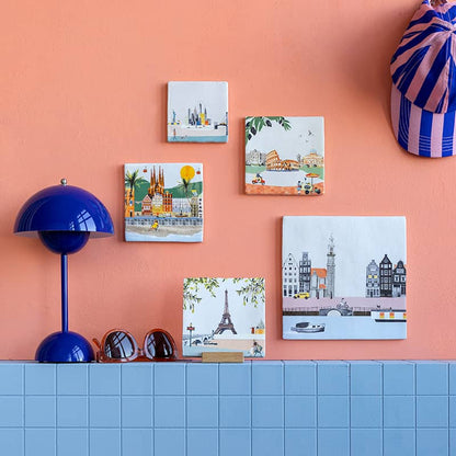 Tegeltjes Parijs, Amsterdam, Rome op muur met oranje achtergrond