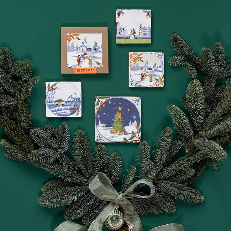 Kersttegeltje wintertaferelen omringd door groene dennentakken en strik