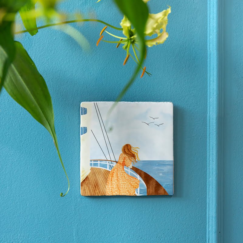 Tegeltje met vrouw op schip tegen blauwe wand