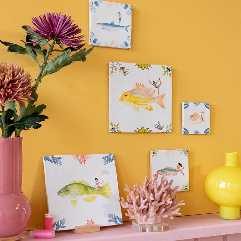 Tegeltje visserkunst thuis aan pastelgele muur gepresenteerd