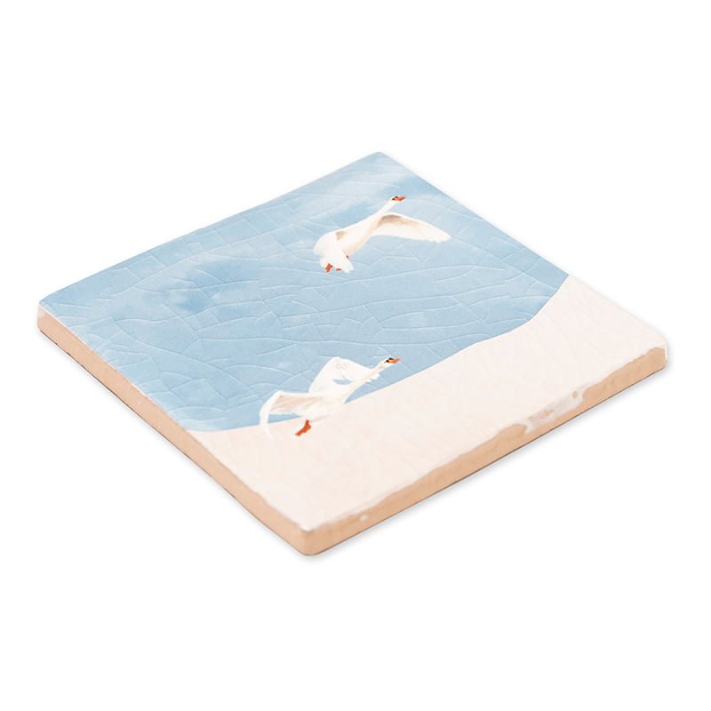 Tegeltje met vliegende zwanen op een blauwe achtergrond