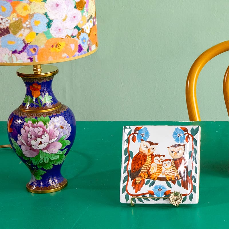 Geboortetegel met drie uilen, geplaatst naast kleurrijke lamp