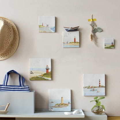 Tegeltjes met vuurtorens tegen muur met decoraties en hoed