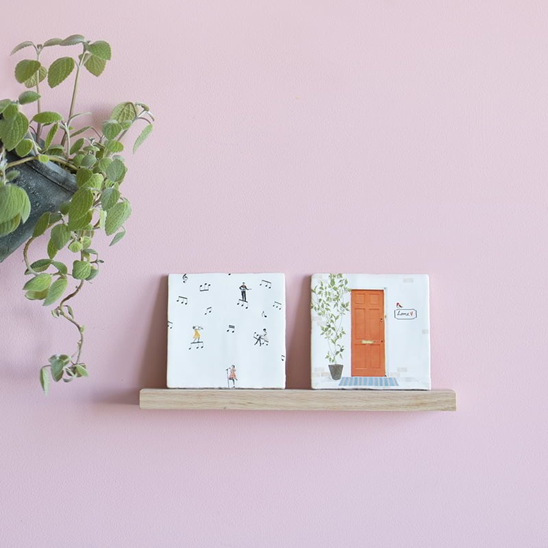 Wandplankje met twee tegeltjes op roze muur