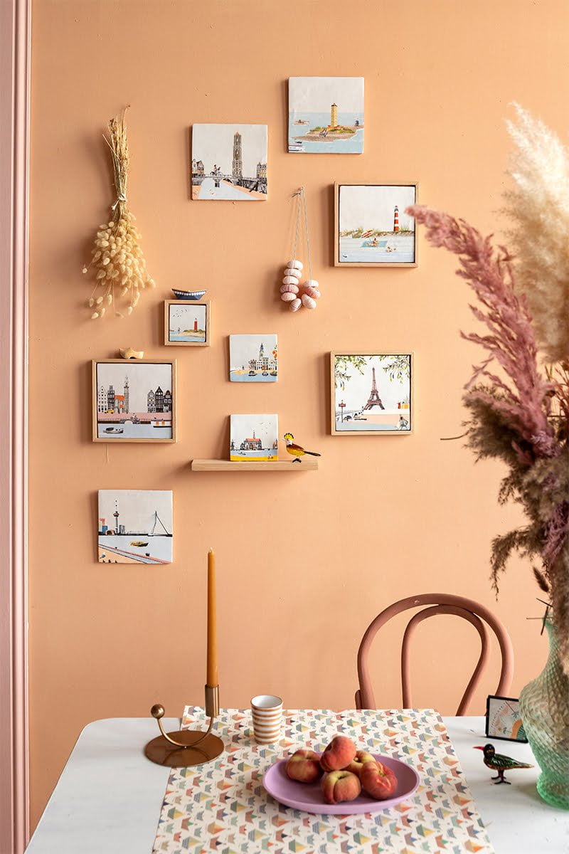Tegeltjes verschillende steden aan oranje muur boven eetkamertafel