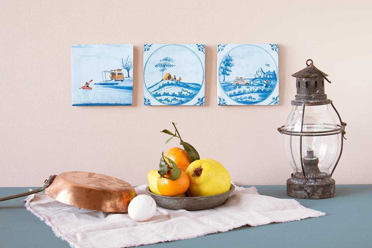 Delfts blauw tegeltje met kampeerders en landschap, op muur bevestigd