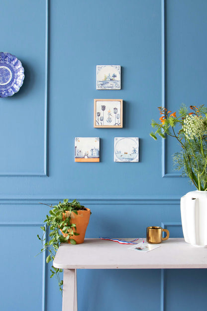 Delfts blauw tegeltje met tulpen op blauwe muur bevestigd